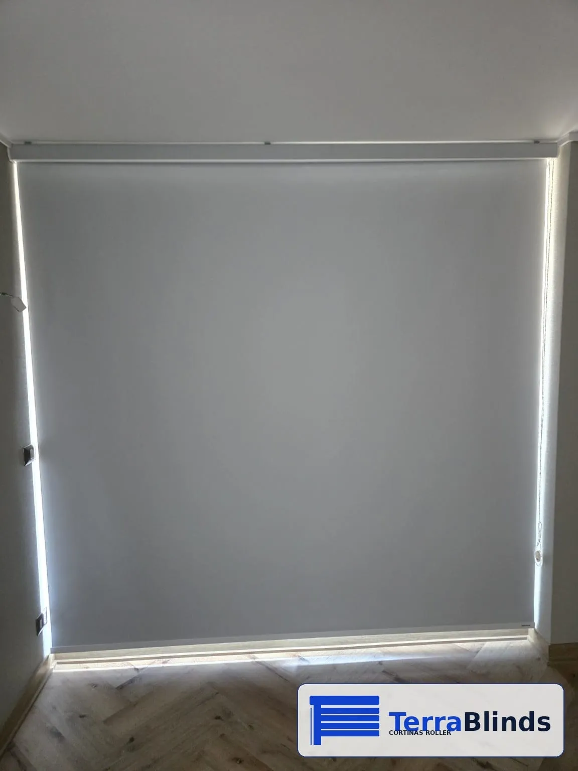 Cortina roller blackout gris instalada en un dormitorio