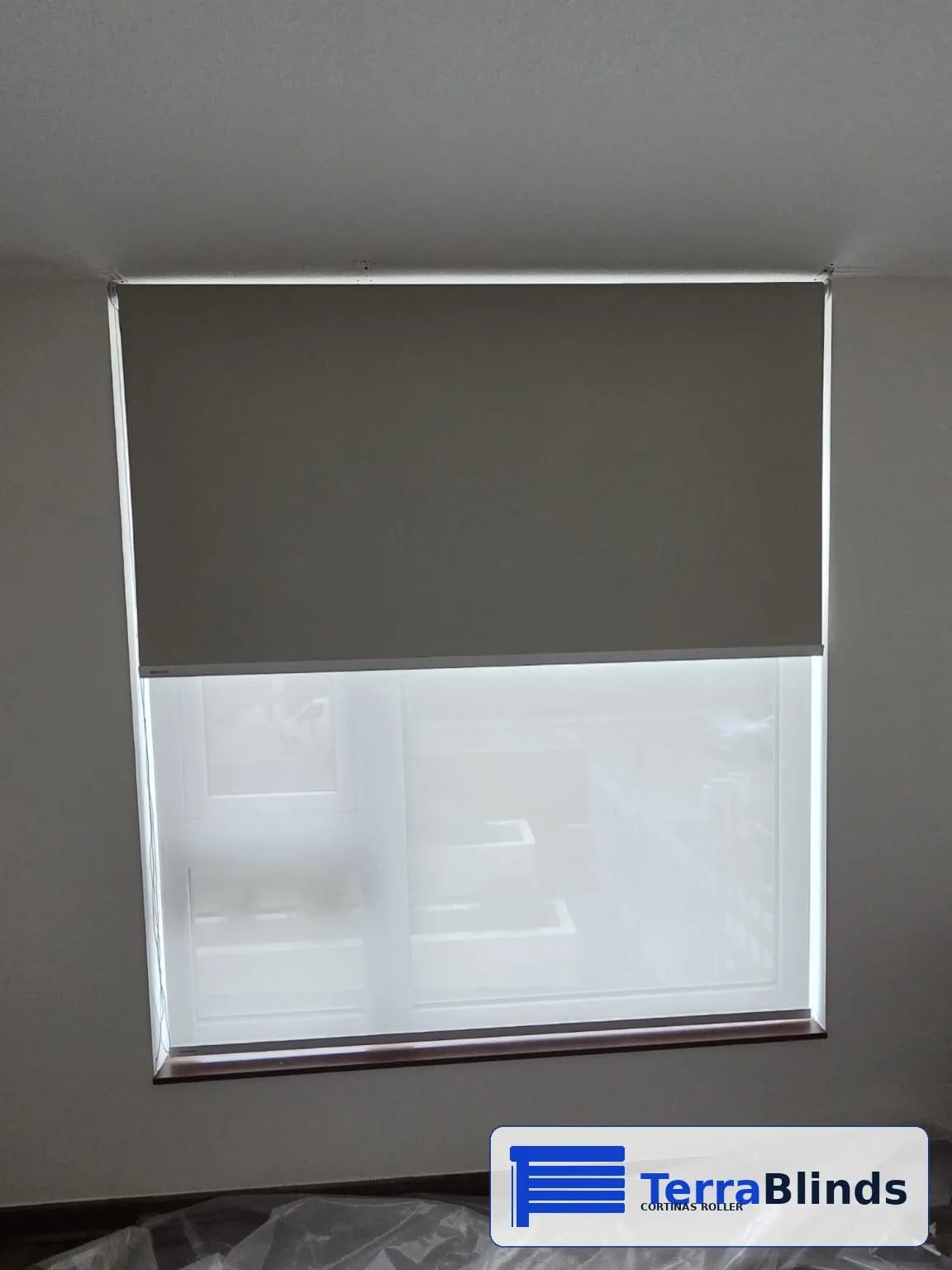 Cortina roller blackout a medio bajar, instalada por TerraBlinds